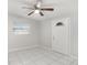 Bright bedroom features tile flooring, a ceiling fan, a window, and a white front door at 3308 W Walnut St, Tampa, FL 33607