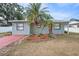 Charming single-story home featuring a red driveway, mature palm trees, and tidy landscaping at 3308 W Walnut St, Tampa, FL 33607
