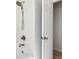 Bathroom with white tile, shower head and bath with door to an adjacent room at 3619 W Leona St, Tampa, FL 33629