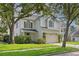 Traditional two-story home with white brick and siding, lush landscaping, and a bench in the front yard at 3619 W Leona St, Tampa, FL 33629