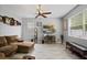 Cozy living room featuring gray walls, wood-look floors, a ceiling fan, and a large window for natural light at 396 Winthrop Dr, Spring Hill, FL 34609