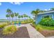 Charming front yard with blue Adirondack chairs, brick pavers, lush landscaping, and picturesque water views lined with palm trees at 401 Whitcomb Blvd, Tarpon Springs, FL 34689