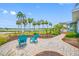 Charming front yard with blue Adirondack chairs, brick pavers, lush landscaping, and picturesque water views lined with palm trees at 401 Whitcomb Blvd, Tarpon Springs, FL 34689