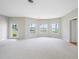 A bright living room featuring neutral carpeting, new paint, and large windows that offer a beautiful view at 401 Whitcomb Blvd, Tarpon Springs, FL 34689