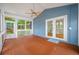 Bright sunroom with wood flooring, ceiling fan, and multiple windows offering serene views of the yard at 401 Whitcomb Blvd, Tarpon Springs, FL 34689