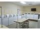 Well-lit laundry room featuring multiple washing machines, folding table, and laundry carts for residents' convenience at 4345 Tahitian Gardens Cir # C, Holiday, FL 34691