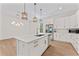 Well-lit kitchen featuring an island with sink, pendant lighting, stainless steel appliances, and white cabinetry at 4911 N Nebraska Ave, Tampa, FL 33603