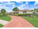 Attractive one-story home showcasing a well-manicured lawn and a curving red brick driveway at 5112 Lanai Way, Tampa, FL 33624