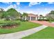A two car garage features a lush green yard with manicured shrubs and mature trees at 5112 Lanai Way, Tampa, FL 33624
