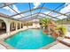 Screened-in pool featuring a custom rock waterfall, mature landscaping, an arched covered patio, and a bar at 5112 Lanai Way, Tampa, FL 33624