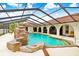 Screened-in pool featuring a custom rock waterfall, mature landscaping, and an arched covered patio at 5112 Lanai Way, Tampa, FL 33624