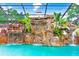 Inviting pool with a custom rock waterfall feature and tropical plants under a screened enclosure at 5112 Lanai Way, Tampa, FL 33624