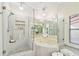 Bright bathroom with a glass shower, jacuzzi tub, neutral tile, and decorative pendant lighting at 531 Sandy Hook Rd, Treasure Island, FL 33706
