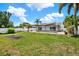Large backyard with a sail-shaded patio area, mature palm trees, and a white fence at 5875 Darren N Ct, Clearwater, FL 33760