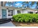 Close up of entryway with a carved blue door, gray steps and green bushes at 6120 5Th N Ave, St Petersburg, FL 33710
