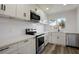 Well-lit modern kitchen featuring stainless steel appliances, white cabinetry, and gray wood-style floors at 6120 5Th N Ave, St Petersburg, FL 33710