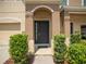 Home exterior with a dark front door framed by arched portico, lush green bushes and manicured landscaping at 6912 40Th N Ln, Pinellas Park, FL 33781