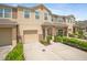 Two-story tan townhome with a one-car garage, green bushes and well maintained driveway at 6912 40Th N Ln, Pinellas Park, FL 33781