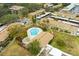 A bird's-eye view displays a pool amidst the complex, surrounded by mature trees, buildings, and parking spaces at 7606 Woodbridge Blvd, Tampa, FL 33615