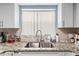 Close up of the kitchen sink and granite countertops, with white cabinetry at 7606 Woodbridge Blvd, Tampa, FL 33615