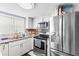 Close up of the kitchen featuring stainless appliances, white cabinetry, and tile flooring at 7606 Woodbridge Blvd, Tampa, FL 33615