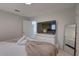 Bright bedroom with modern TV, dresser, full length mirror, and neutral-toned decor at 8117 Bay Dr, Tampa, FL 33635