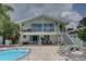 Two-story house with a patio, pool, outdoor seating, and glass railings for enjoying the view at 8117 Bay Dr, Tampa, FL 33635