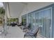 Covered patio boasts comfortable seating, cool ceiling fan, glass railings, and sliding glass doors for indoor/outdoor living at 8117 Bay Dr, Tampa, FL 33635