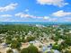 Stunning aerial view showcasing the property in a verdant neighborhood with distant waterfront views and a vibrant blue sky at 895 Joan St, Dunedin, FL 34698