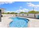 A beautiful pool sits on a grey paver patio with a white fence and blue sky in the background at 895 Joan St, Dunedin, FL 34698