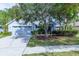 Quaint single-story home with mature trees, garden beds, and a two car garage at 9220 Dayflower Dr, Tampa, FL 33647