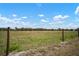 Fenced backyard overlooking a field with a wire fence running through it at 923 Whimbrel Run, Bradenton, FL 34212