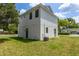 Exterior corner view of white home with dark trim, lush green lawn, and blue sky at 925 E Chelsea St, Tampa, FL 33603