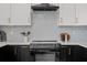 Modern kitchen featuring white cabinets, black countertops, subway tile backsplash and stainless steel appliances at 925 E Chelsea St, Tampa, FL 33603