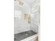 Close-up of a glass shower featuring marble tiles, gold fixtures, and a black tile floor at 925 E Chelsea St, Tampa, FL 33603