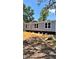 View of single Gathering home with blue siding on blocks surrounded by a tree filled landscape at 10030 Lake Dr, Weeki Wachee, FL 34613