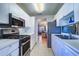 Efficient kitchen featuring white cabinets, stainless steel appliances, and view into the living area at 10037 62Nd N Ter # 9, St Petersburg, FL 33708