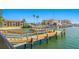 Picturesque view of a wooden dock leading out to the water, buildings and boats in the background at 10355 Paradise Blvd # 412, Treasure Island, FL 33706