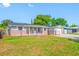 Well-maintained home featuring a gray facade with brick accents, a fenced yard and green lawn at 10825 Oakdale Ave, Port Richey, FL 34668