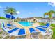 Community pool area with palm trees, building, and blue lounge chairs at 1100 E Bay Dr # 60, Largo, FL 33770
