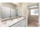 Bright bathroom with double granite vanity and sinks, a large mirror, and entry to another bedroom at 12436 Shining Willow St, Riverview, FL 33579