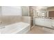 Bright bathroom featuring a soaking tub, glass enclosed shower, white cabinets and tile flooring at 12436 Shining Willow St, Riverview, FL 33579