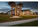 Exterior home view with a three car garage, palm trees, and white rock features in the landscaped area at 12710 Wheatgrass Ct, Parrish, FL 34219