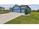 Three car garage of a blue single story home with a green lawn at 12710 Wheatgrass Ct, Parrish, FL 34219