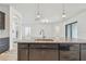 Granite kitchen island with a stainless steel sink, dishwasher, and dark cabinetry at 12710 Wheatgrass Ct, Parrish, FL 34219