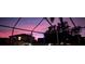 Sunset sky seen through pool cage, with a silhouette of trees and home in the background at 1313 Key West Ct, Wesley Chapel, FL 33544