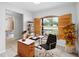 Bright home office featuring a modern desk, wooden shutters, and a view of the front yard at 14128 Pomona Ave, Spring Hill, FL 34609