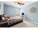 Blue bedroom with a neatly made bed, wall decor, a mounted TV, and a sunny window view at 15507 Caynor Ash Ln, Sun City Center, FL 33573