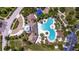 Aerial view of a community pool with a modern bathhouse and lush landscaping at 15507 Caynor Ash Ln, Sun City Center, FL 33573