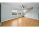 Empty living room showcasing hardwood floors, two large windows, staircase, and ceiling fan at 1864 Clearbrooke Dr, Clearwater, FL 33760